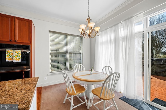 carpeted dining room with an inviting chandelier, baseboards, and ornamental molding