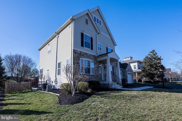 view of front of house with stone siding, a front yard, and fence