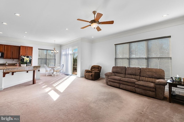 living room with recessed lighting, light colored carpet, ornamental molding, and ceiling fan with notable chandelier