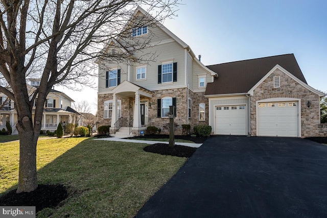 traditional-style home with a front lawn, stone siding, a garage, and driveway