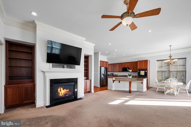 unfurnished living room featuring light colored carpet, ceiling fan with notable chandelier, and crown molding