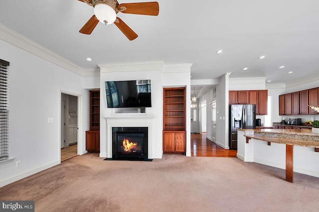 unfurnished living room with a ceiling fan, baseboards, a fireplace with flush hearth, recessed lighting, and light colored carpet