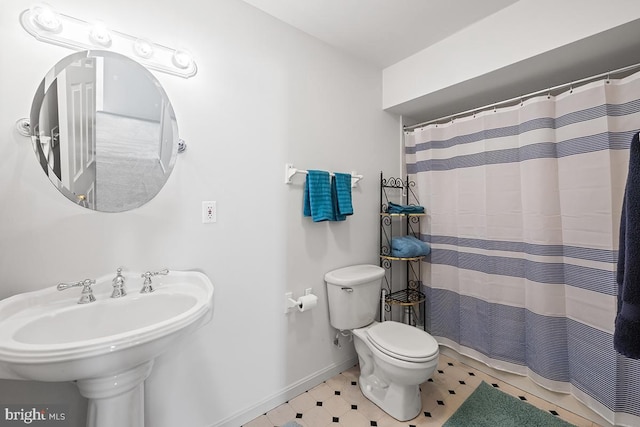 full bathroom with a sink, curtained shower, baseboards, and toilet