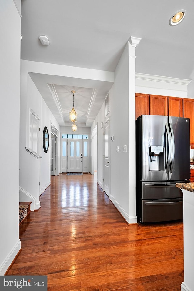 foyer featuring a notable chandelier, wood finished floors, baseboards, and ornamental molding