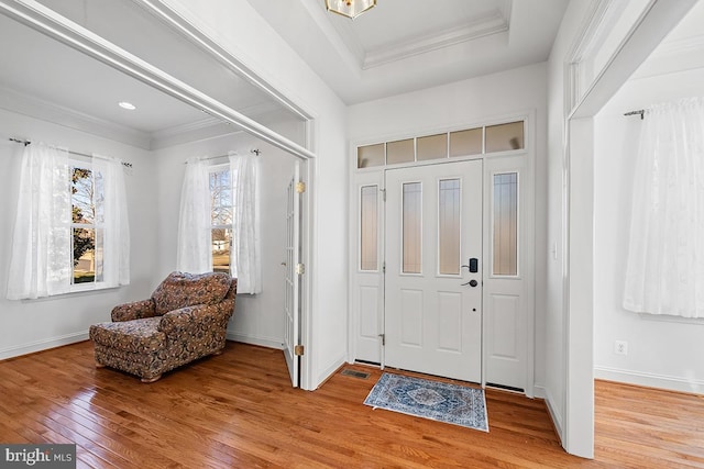 foyer entrance featuring crown molding, light wood-style flooring, and baseboards