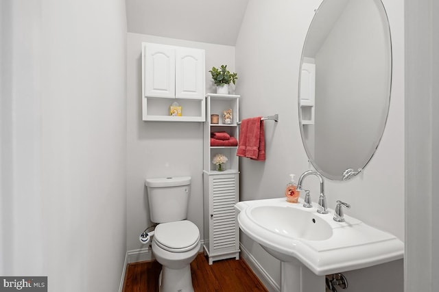 half bath featuring a sink, toilet, baseboards, and wood finished floors