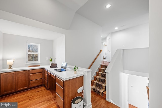 kitchen featuring a peninsula, recessed lighting, light countertops, light wood-style floors, and brown cabinets