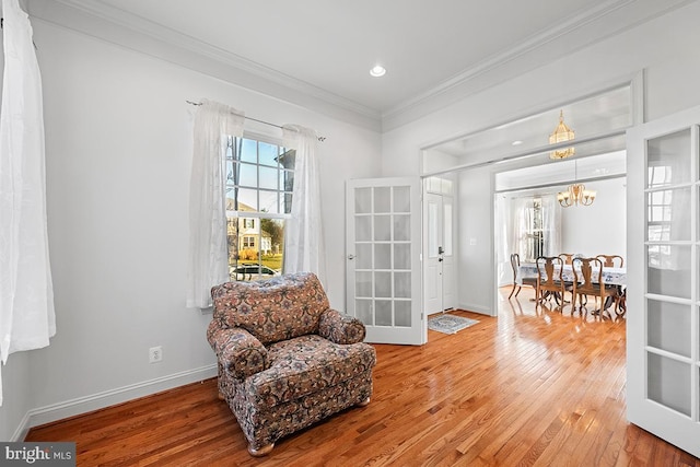 living area with an inviting chandelier, crown molding, plenty of natural light, and wood-type flooring