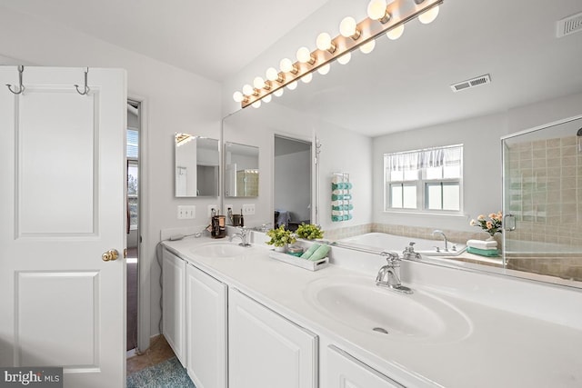 bathroom featuring double vanity, a bath, visible vents, and a sink