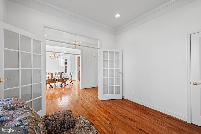 interior space featuring french doors, an inviting chandelier, hardwood / wood-style floors, and crown molding