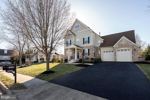 view of front of home featuring a front lawn, an attached garage, stone siding, and driveway