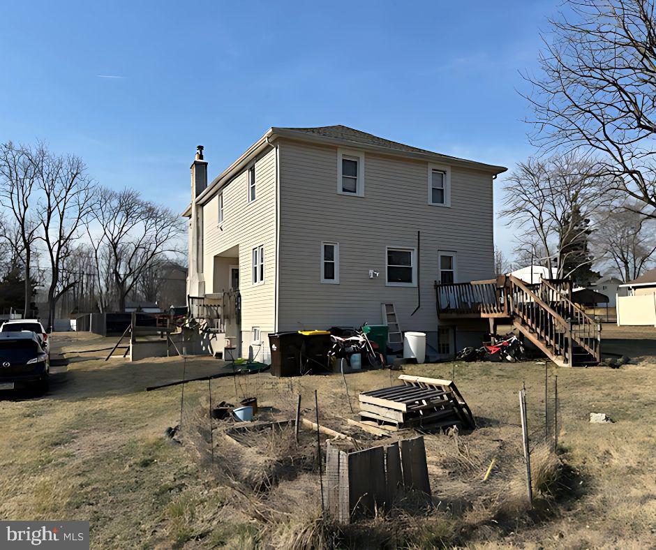 rear view of property with a chimney, stairs, a deck, and a garden