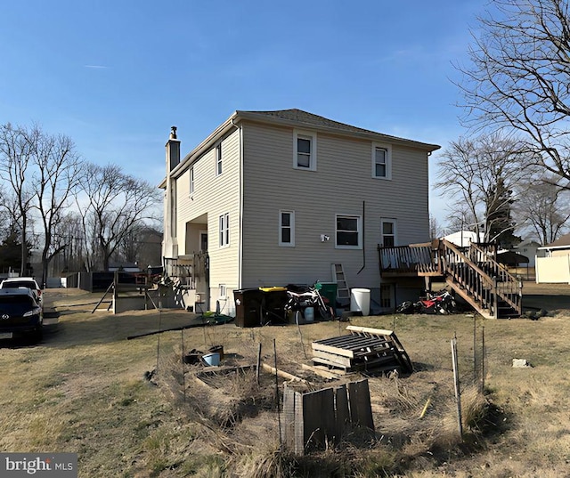 rear view of property with a chimney, stairs, a deck, and a garden