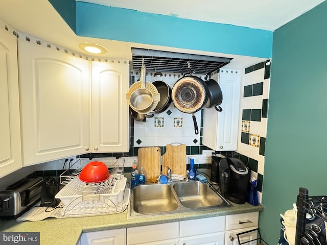 kitchen featuring a sink, tasteful backsplash, and white cabinetry