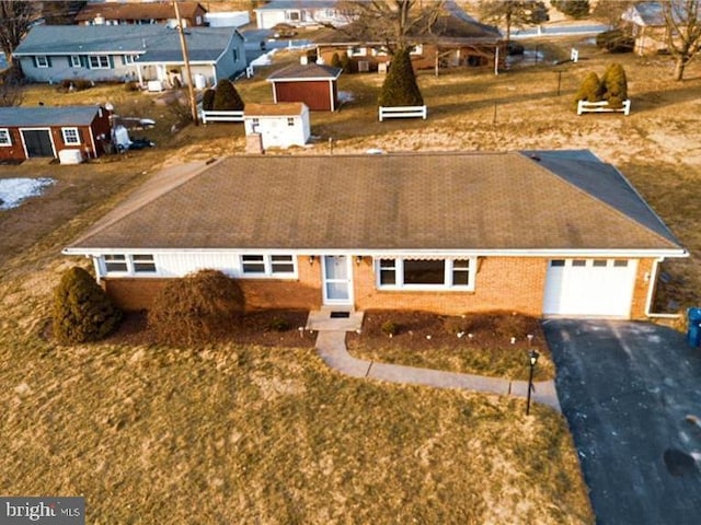 view of front of property featuring an attached garage, a residential view, brick siding, and driveway