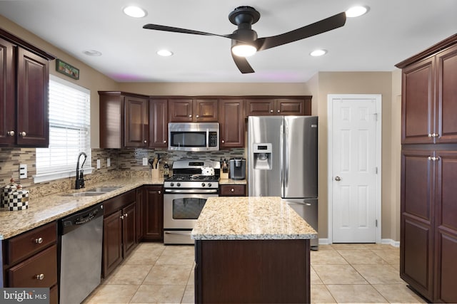 kitchen with a sink, stainless steel appliances, decorative backsplash, and a center island