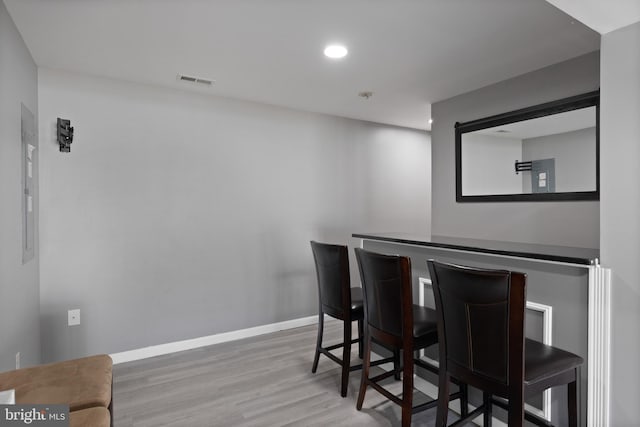 dining space with visible vents, wood finished floors, recessed lighting, a bar, and baseboards