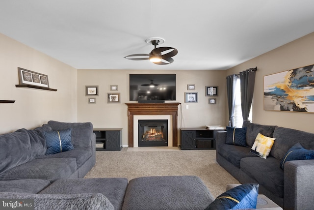 carpeted living area featuring a glass covered fireplace and a ceiling fan