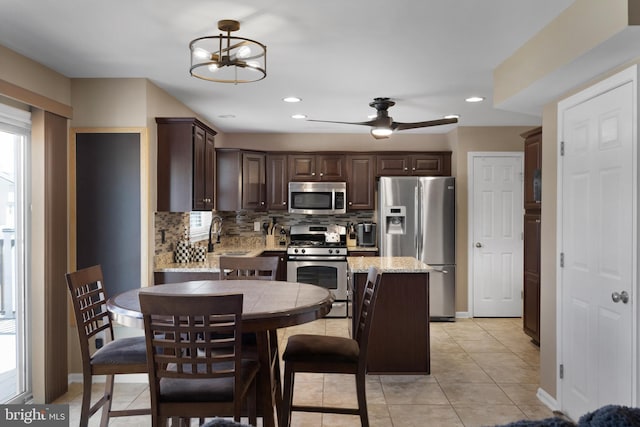 kitchen with tasteful backsplash, recessed lighting, stainless steel appliances, dark brown cabinetry, and light tile patterned floors