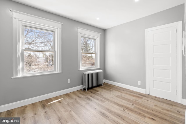 unfurnished room with radiator, recessed lighting, baseboards, and light wood-type flooring