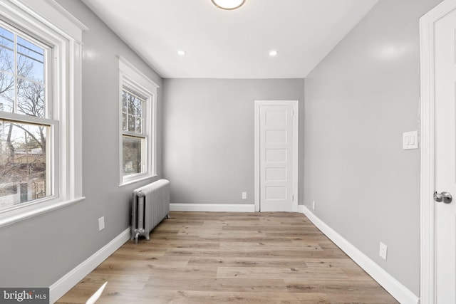 spare room with radiator heating unit, recessed lighting, baseboards, and light wood-type flooring