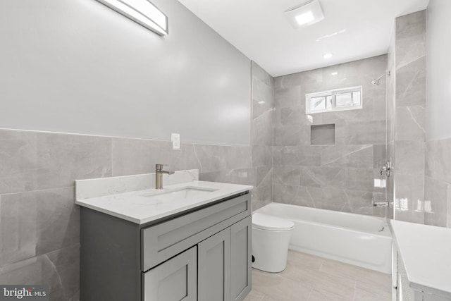 full bathroom with a wainscoted wall, toilet, shower / tub combination, tile walls, and vanity