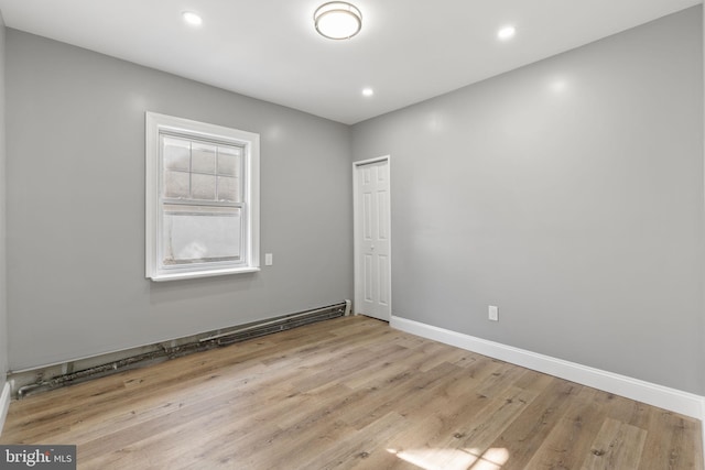 spare room featuring recessed lighting, wood finished floors, baseboards, and a baseboard radiator