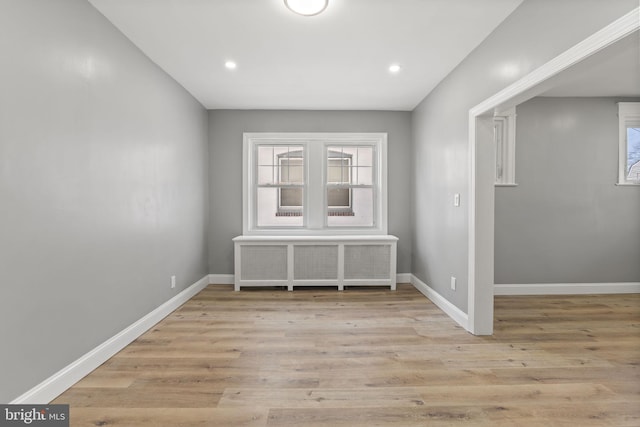 empty room with recessed lighting, baseboards, radiator, and light wood-style flooring