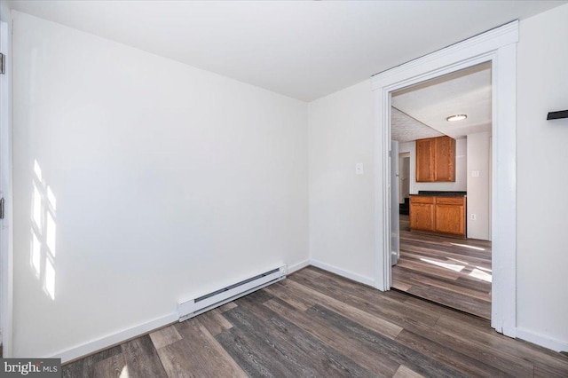 unfurnished room featuring dark wood-style floors, baseboard heating, and baseboards