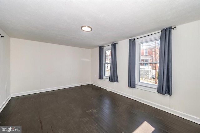 empty room with baseboards, a textured ceiling, and wood finished floors