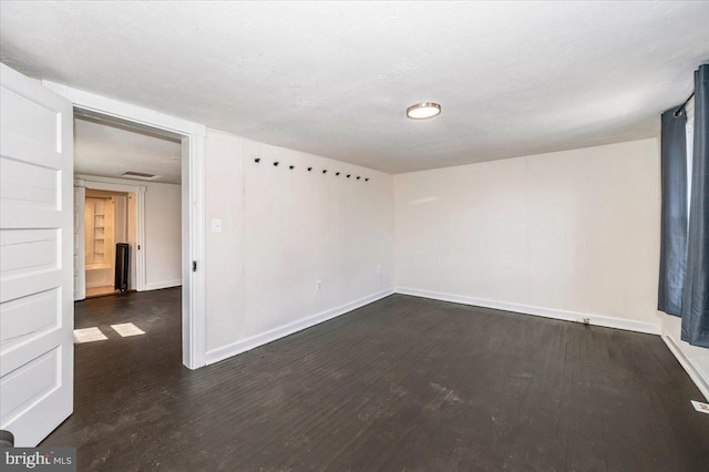 spare room with baseboards and wood finished floors