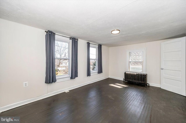 unfurnished room with radiator, a textured ceiling, baseboards, and wood finished floors