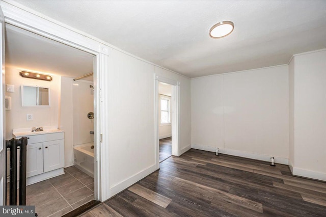 interior space with dark wood finished floors, connected bathroom, baseboards, and a sink