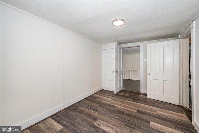 unfurnished bedroom with dark wood finished floors and baseboards