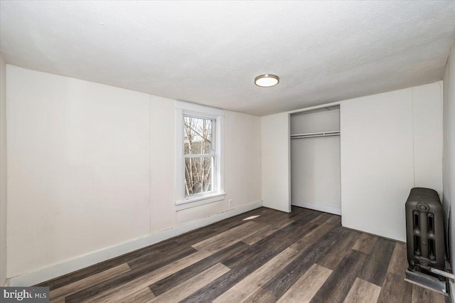 unfurnished bedroom with a closet, baseboards, dark wood-type flooring, and a textured ceiling