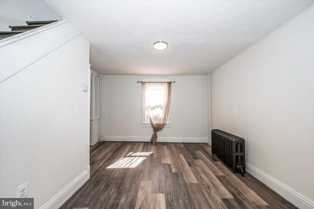 empty room with radiator, baseboards, and wood finished floors