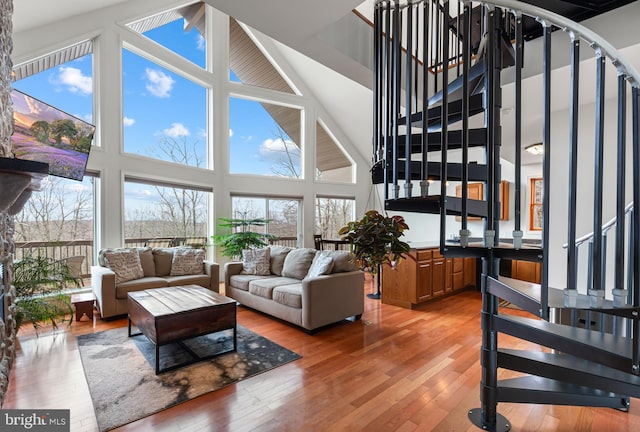 living room featuring stairway, light wood-style flooring, and high vaulted ceiling