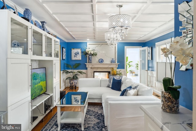 sitting room featuring wood finished floors, a fireplace, a notable chandelier, and coffered ceiling