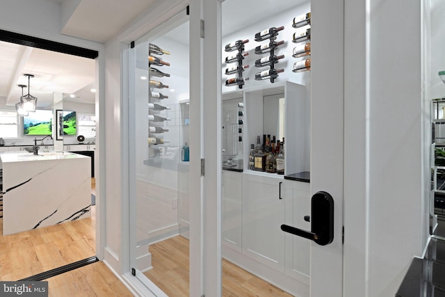 wine room with light wood finished floors and indoor bar