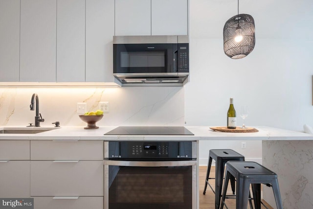 kitchen featuring light countertops, modern cabinets, appliances with stainless steel finishes, and a sink