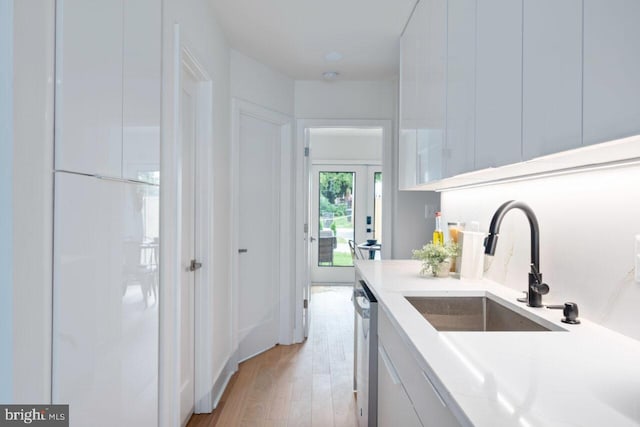 kitchen with a sink, light wood-type flooring, dishwasher, and light countertops