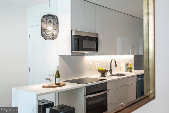 kitchen with modern cabinets, a sink, stainless steel dishwasher, wall oven, and black electric stovetop