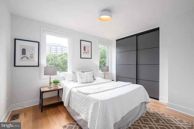 bedroom with visible vents, light wood-type flooring, and baseboards