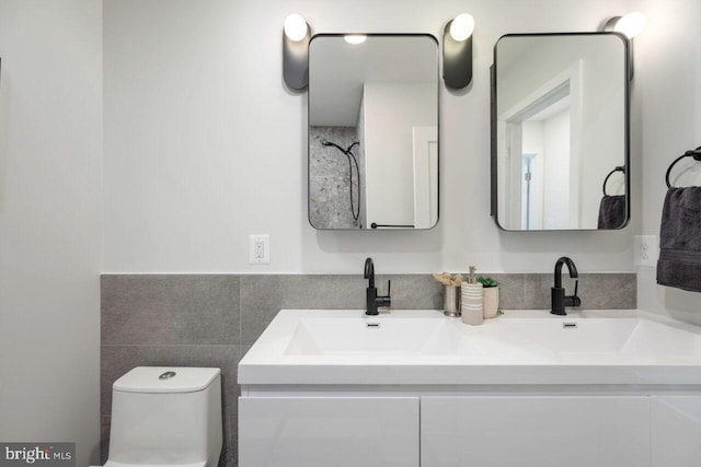 full bathroom with double vanity, toilet, tile walls, and a sink