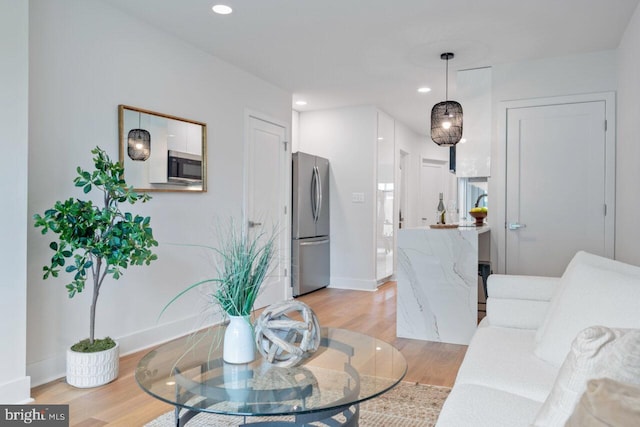 living room with recessed lighting, baseboards, and light wood finished floors