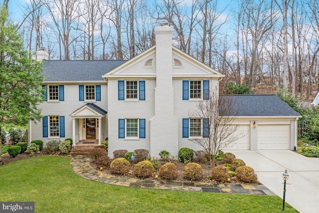 view of front of house featuring an attached garage, a chimney, a front lawn, concrete driveway, and brick siding