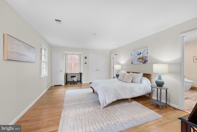 bedroom featuring ensuite bath, visible vents, baseboards, and light wood-type flooring