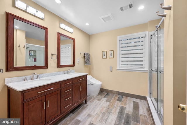 bathroom with visible vents, a shower stall, wood finished floors, and a sink