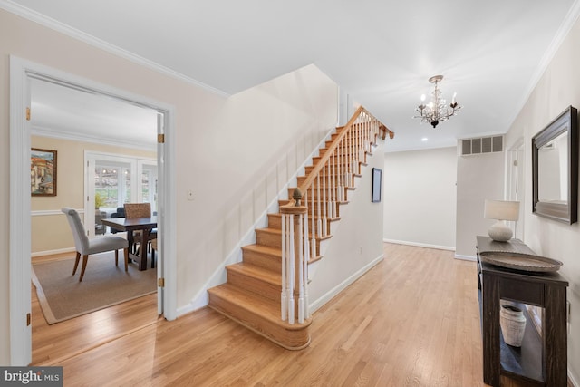 stairway with wood finished floors, visible vents, baseboards, an inviting chandelier, and crown molding