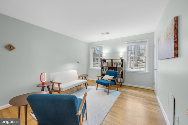 living area featuring visible vents, baseboards, and light wood finished floors